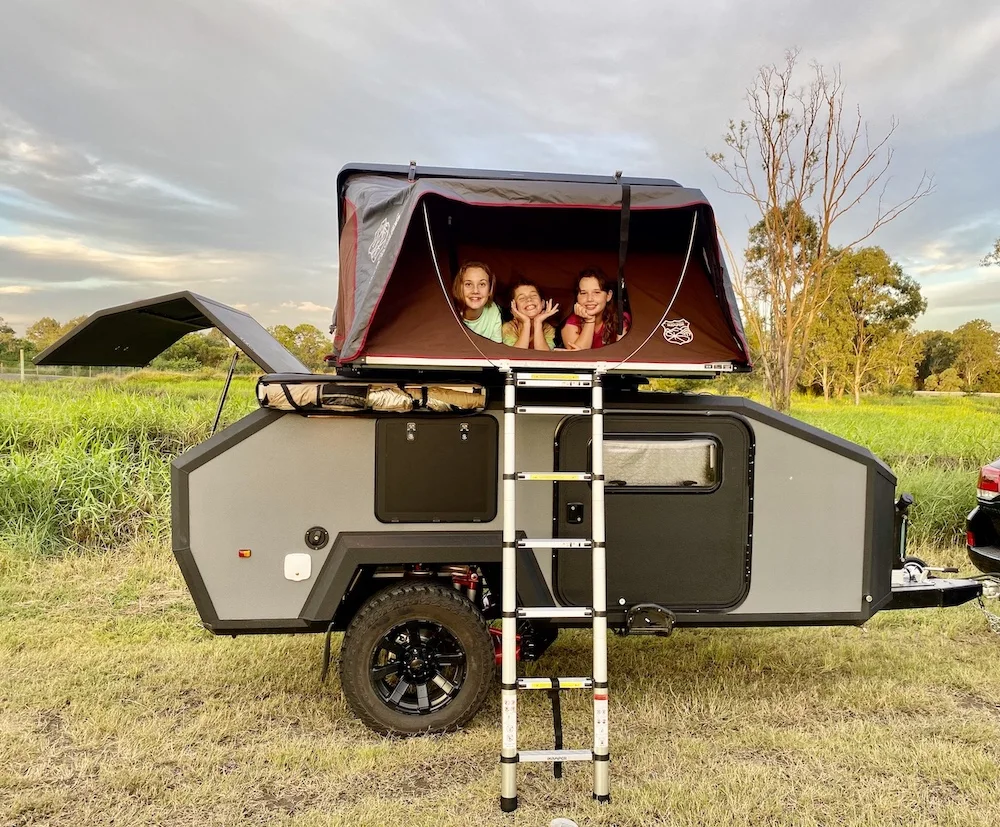 3 Children inside a rooftop tent on top of an off road teardrop camper