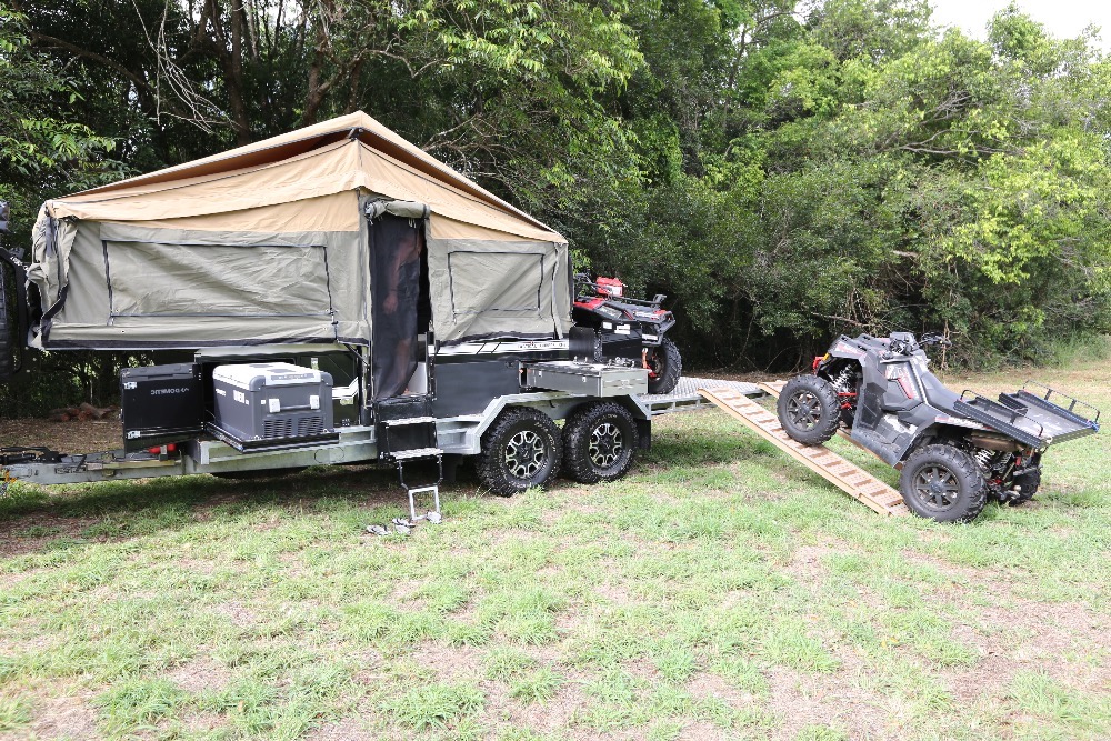 Camper trailer exterior showing the tent set up and quad bikes being loaded on to the toy hauler trailer.