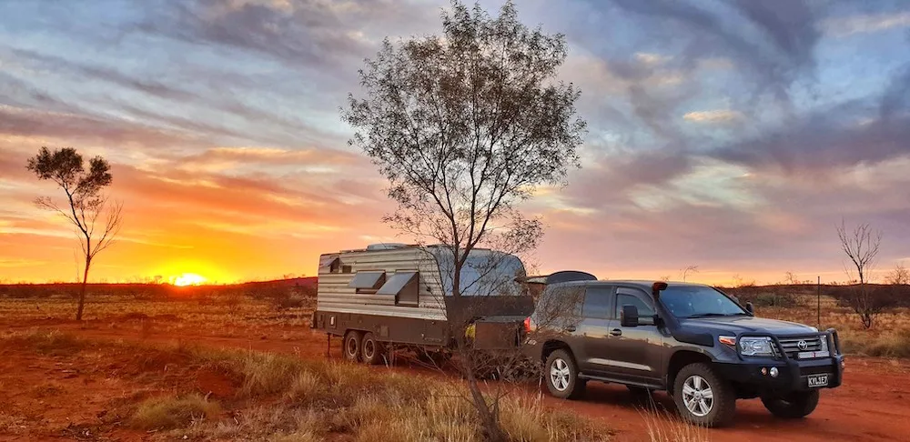 Car and caravan in the Australian outback at sunset