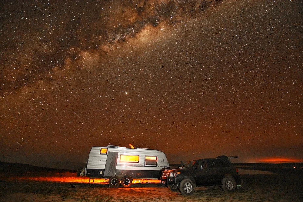 Car and caravan under a starry sky