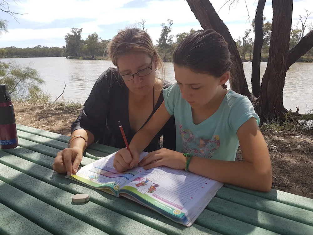 Woman and child doing schoolwork beside the Murray River, VIC Australia