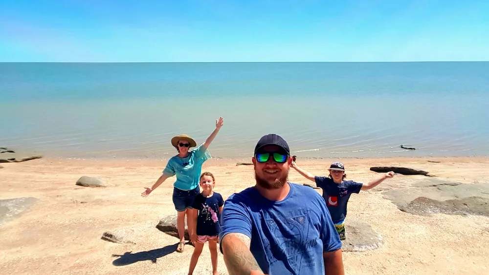 Family posing in front of large body of water in Australia