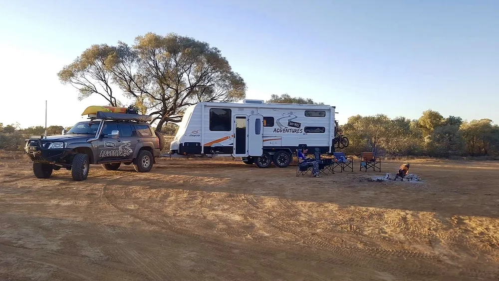 Car and caravan set up for camping in dusty outback Australia