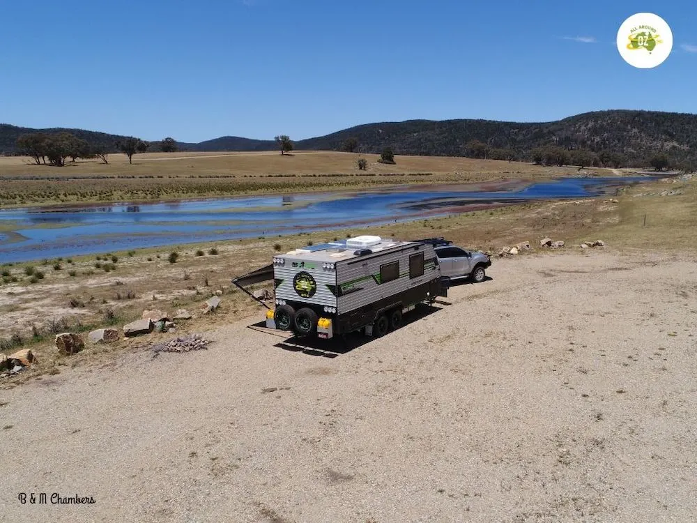 Car and caravan set up beside body of water