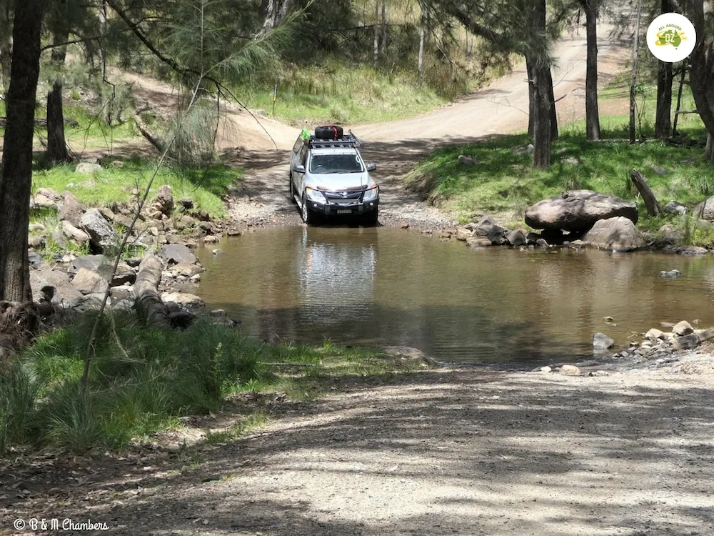 Sliver ute crossing a shallow river
