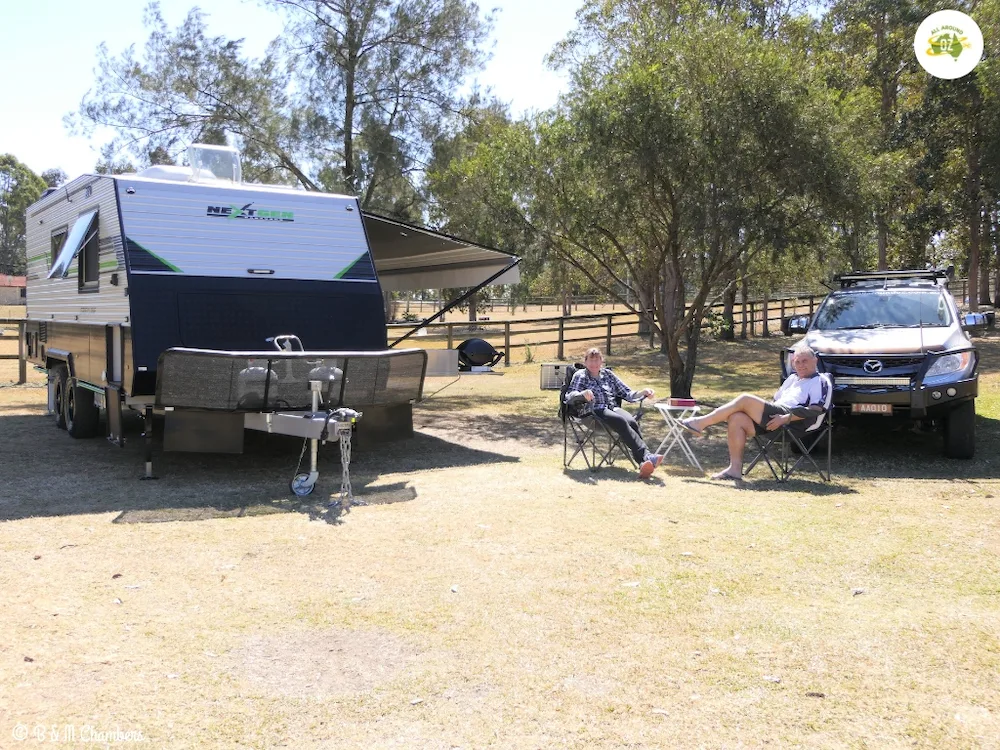 Couple sitting on camp chairs outside their caravan.