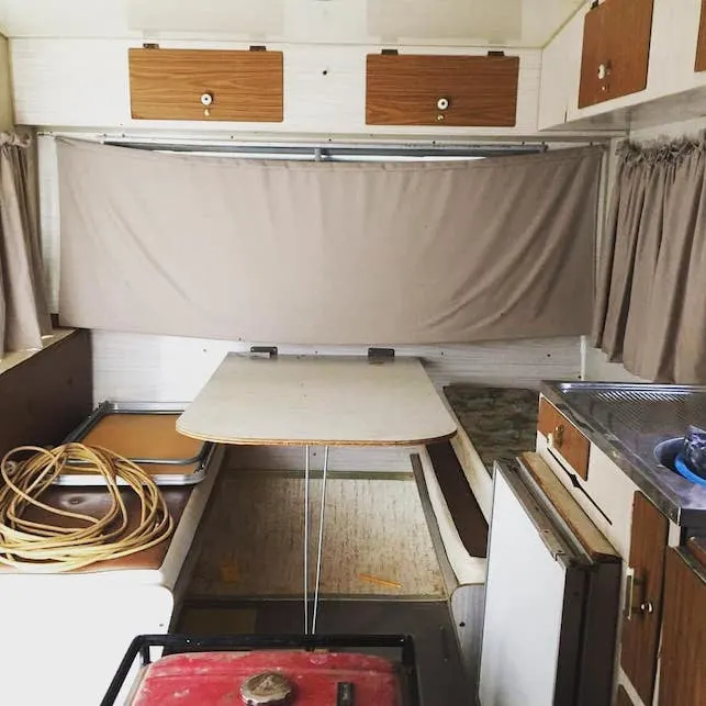 Dinette area inside a vintage caravan that is untidy and worn