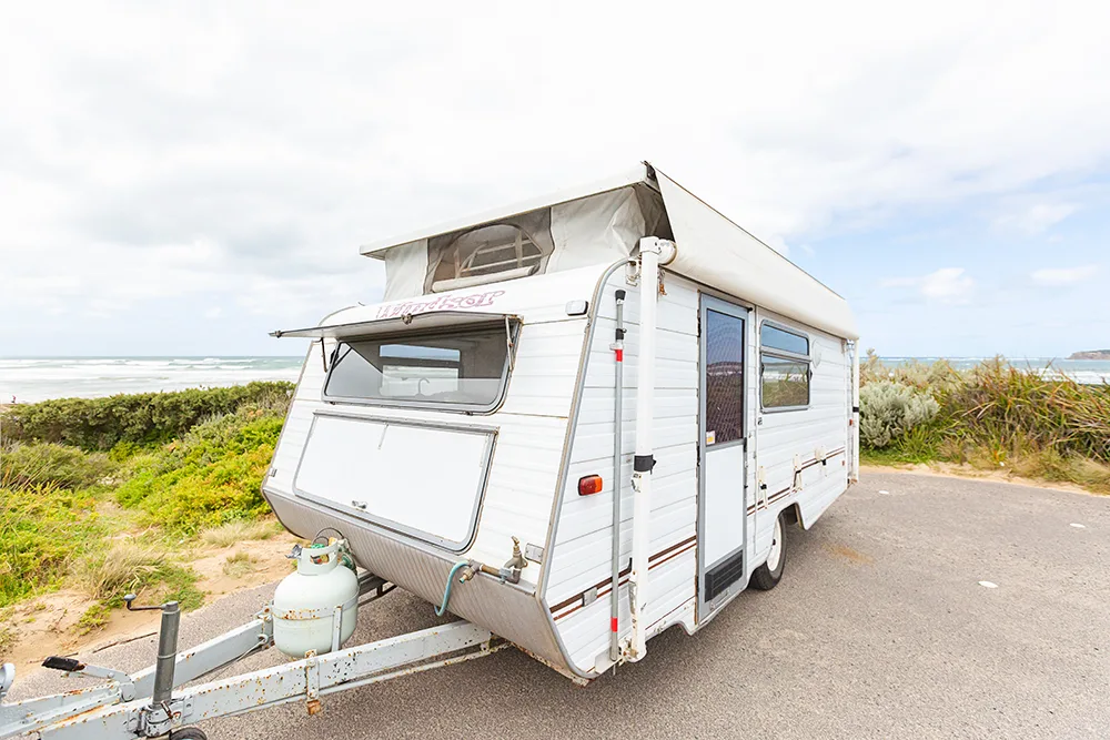Vintage pop top caravan parked at a beach location