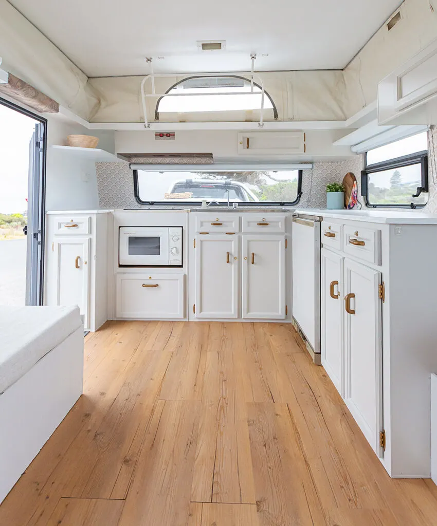 White kitchen cabinets inside a renovated vintage pop-top caravan