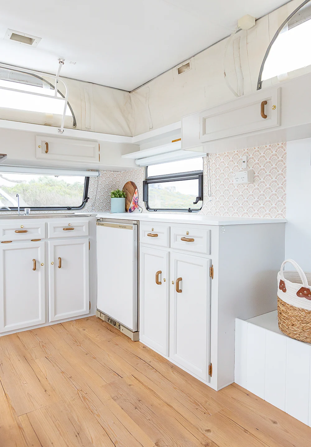 White kitchen cabinets inside a renovated vintage pop-top caravan