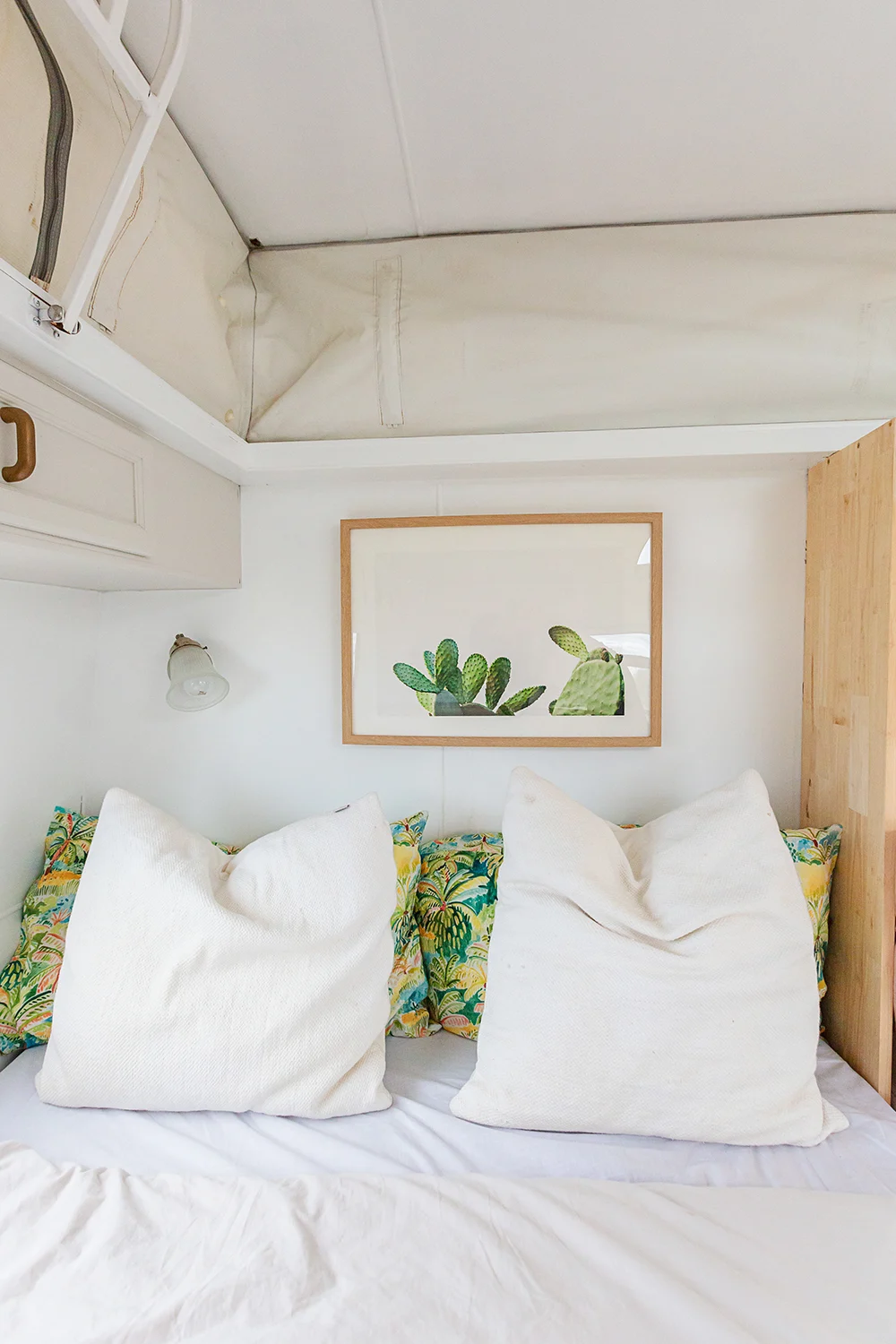 White bed with a cactus artwork above the pillows