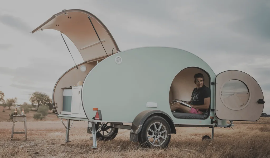 Pale green retro style teardrop camper with side and rear doors open.