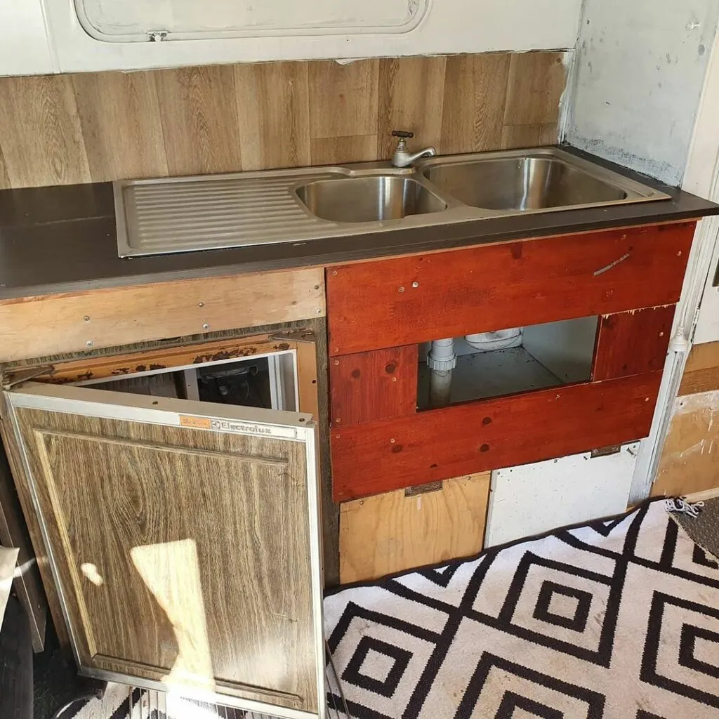 Old and damaged kitchen cabinets in a vintage Viscount caravan before being renovated.