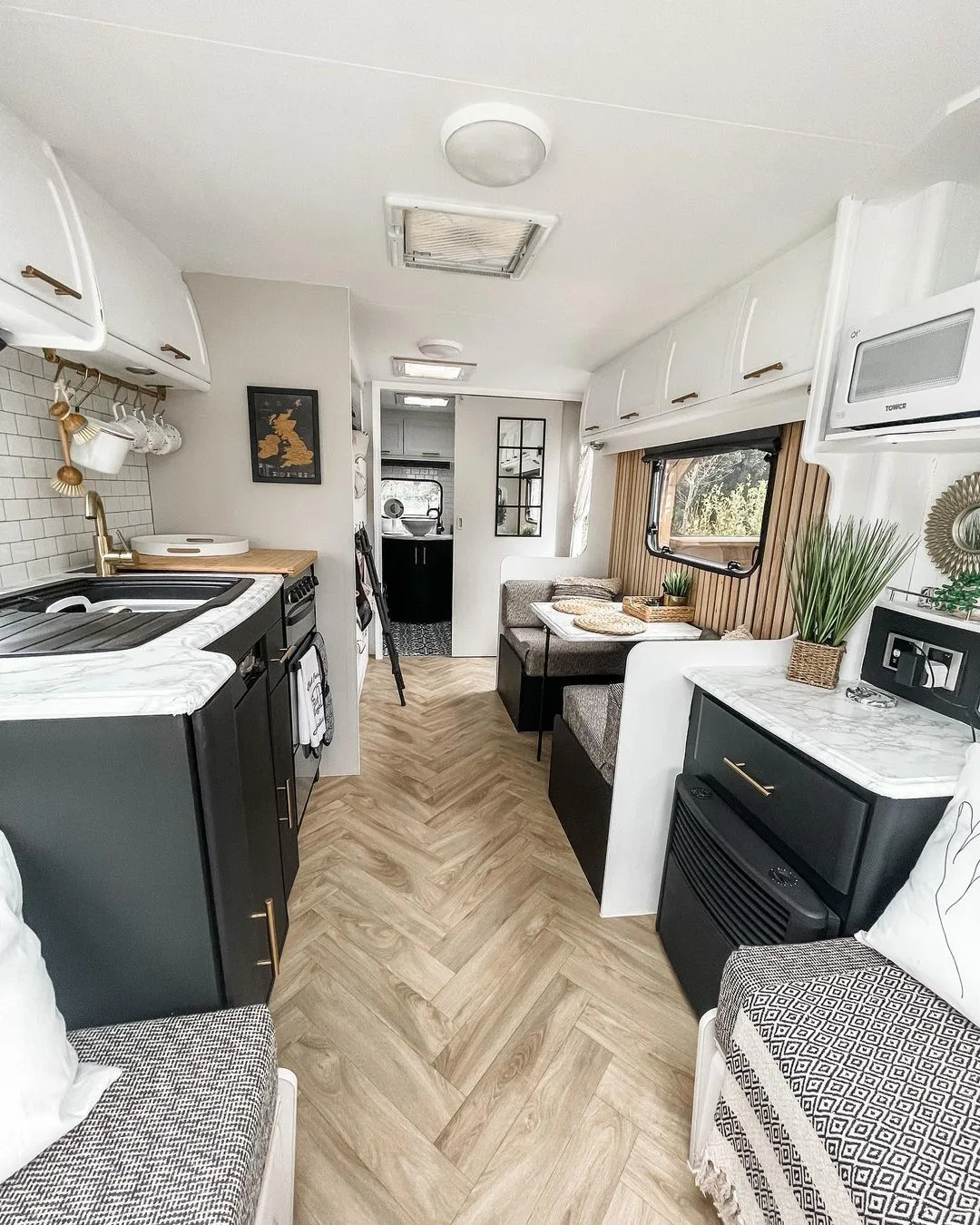 Interior of a renovated caravan with black cabinets and neutral decor.
