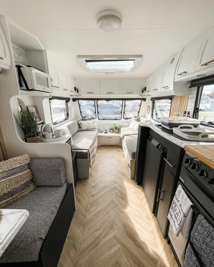 Interior of a renovated caravan showing neutral decor and black ktichen cabinets.