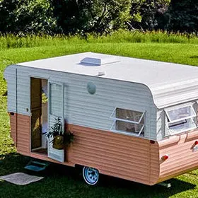 Exterior of a renovated caravan with pink and white paint work.