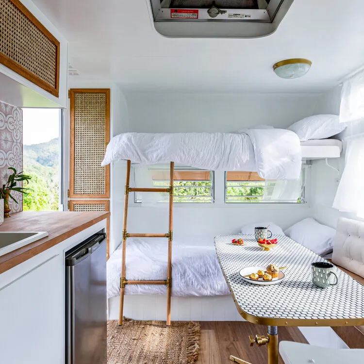Bunks inside a renovated vintage caravan, with natural and white decor.