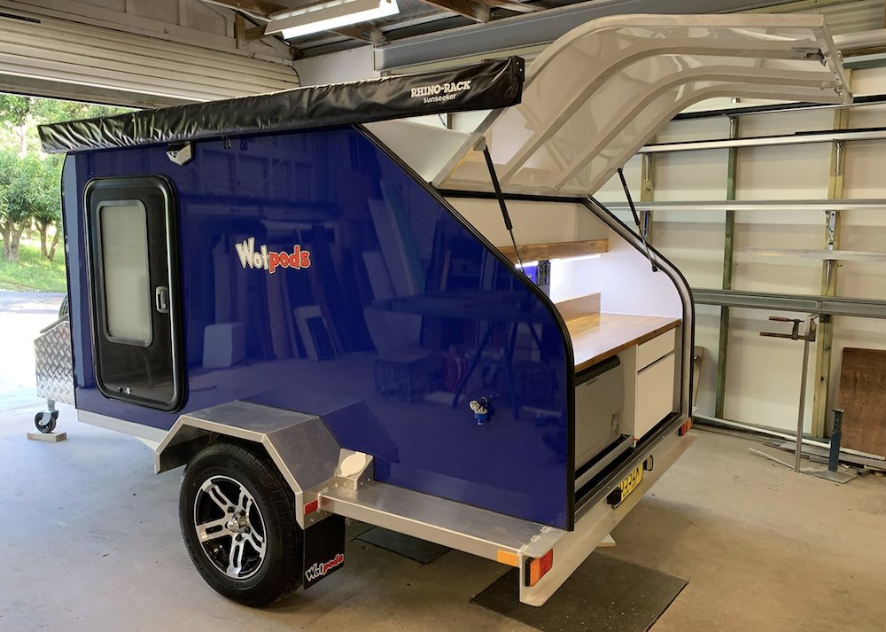 Blue Wot Pods teardrop camper with the rear door open showing the kitchen.