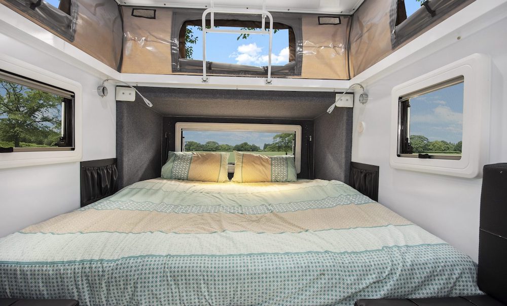 Interior of an Eagle Camper Trailers Warrior 10 hybrid camper, showing the queen size bed.