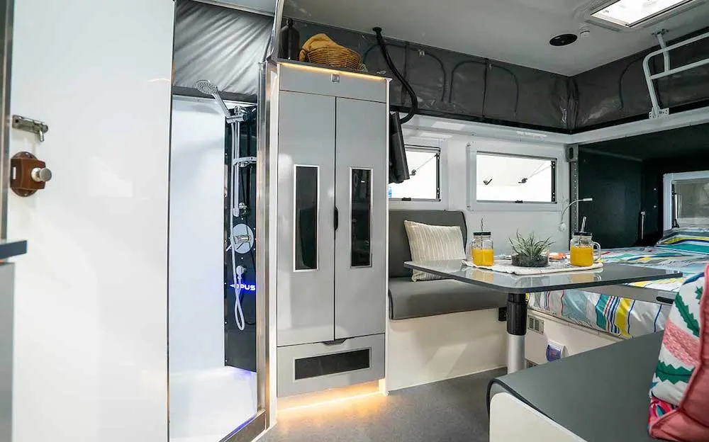 Interior of the Opus OP13 hybrid caravan showing the bed, seating storage.