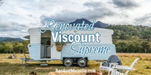 Renovated blue and white vintage caravan in a field with white lawn chairs arranged in front with text that reads: Renovated Viscount Supreme.