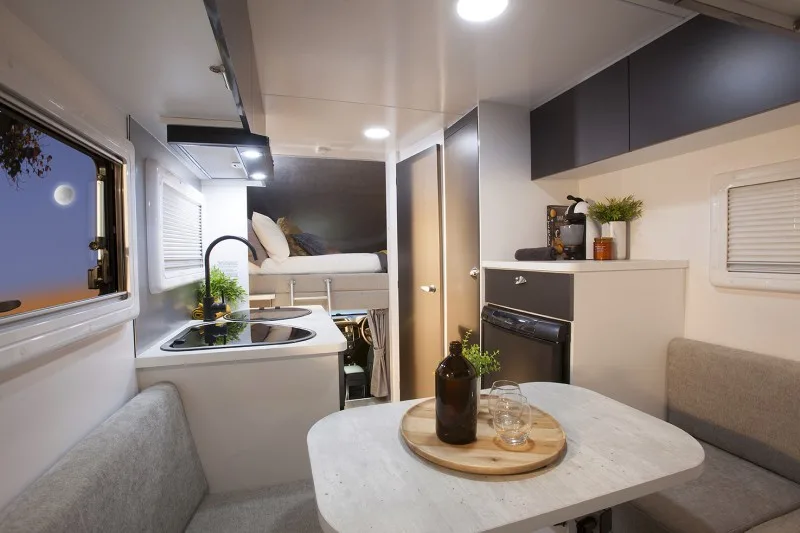 Sunliner Chase motorhome interior showing the dining and kitchen area and the bed in the luton peak.