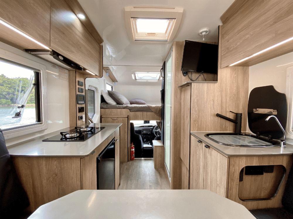 Interior of the Suncamper Sherwood Conqueror motorhome, looking towards the front showing the kitchen and bed above the cab.