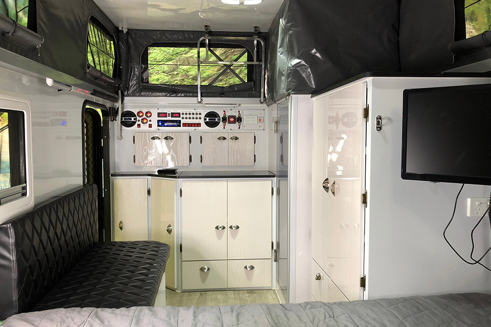 Interior view of the Long Haul Campers T-Rex T13 pop top camper, showing the kitchen and bathroom end.