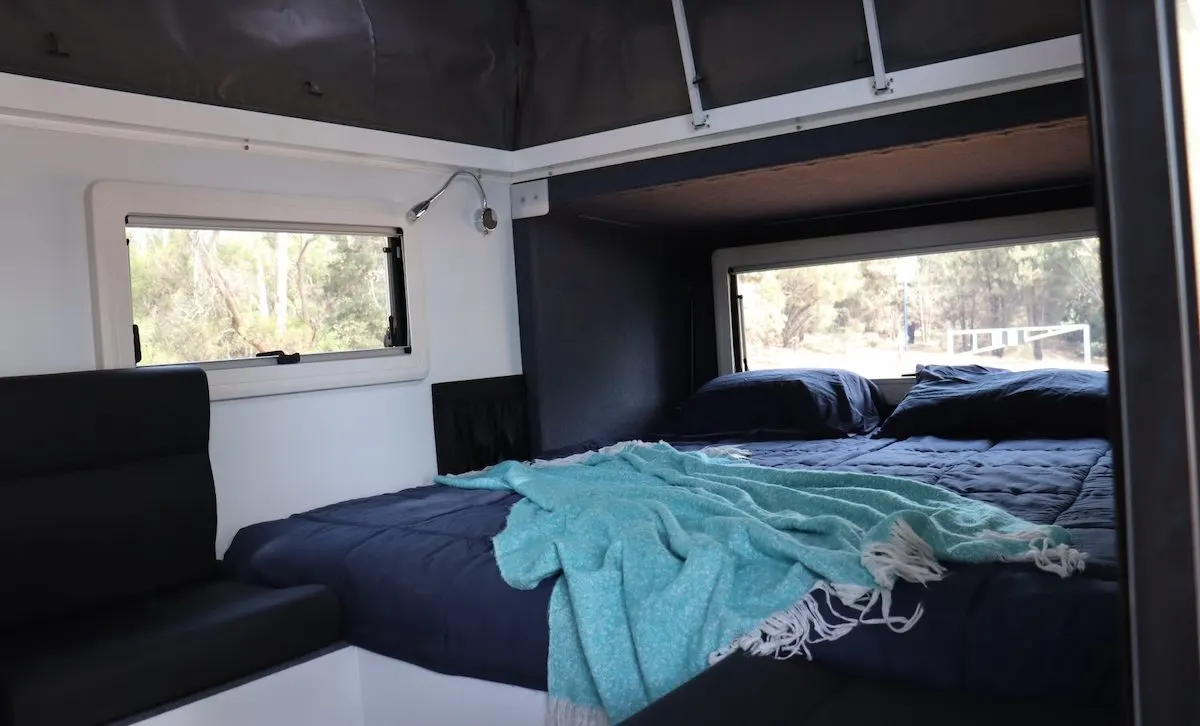 Interior of an Eagle Camper Trailers Warrior 10 hybrid camper, showing the queen size bed.
